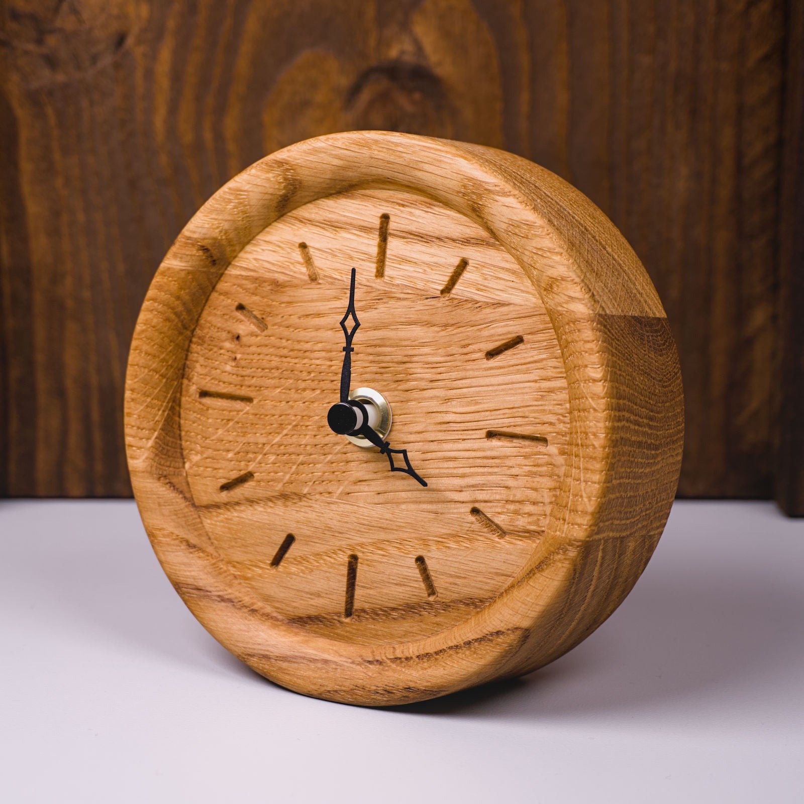 Runde Standuhr aus klassisch geölter Eiche mit eingefrästen Stundenmarkierungen – linke Frontseitenansicht, handgefertigt im Solothurner Unterleberberg von HolzPart.