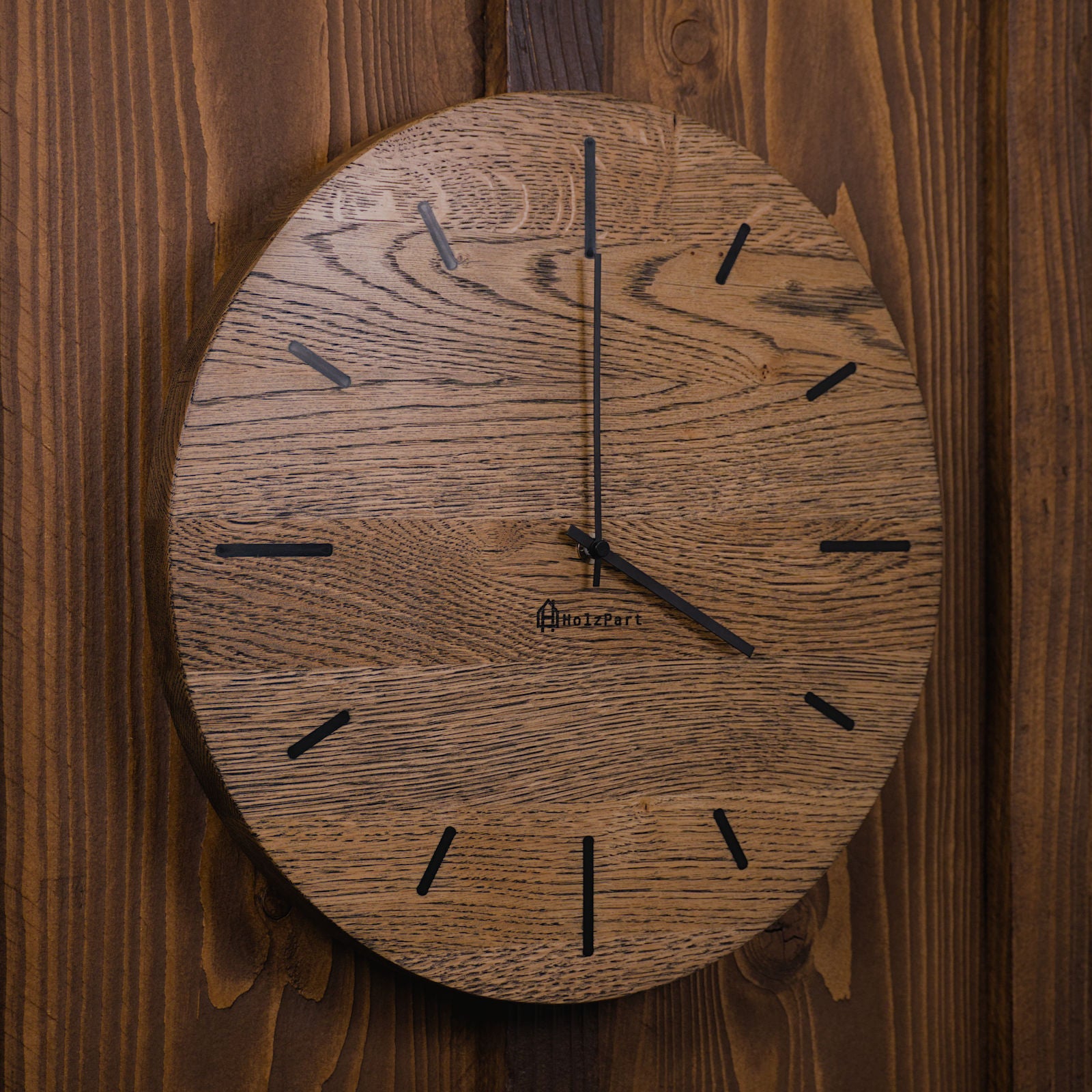 Handgefertigte runde Wanduhr aus colour geölter Eiche mit schwarzen Stundenmarkierungen – Seitenansicht der Uhr von HolzPart Schweiz.