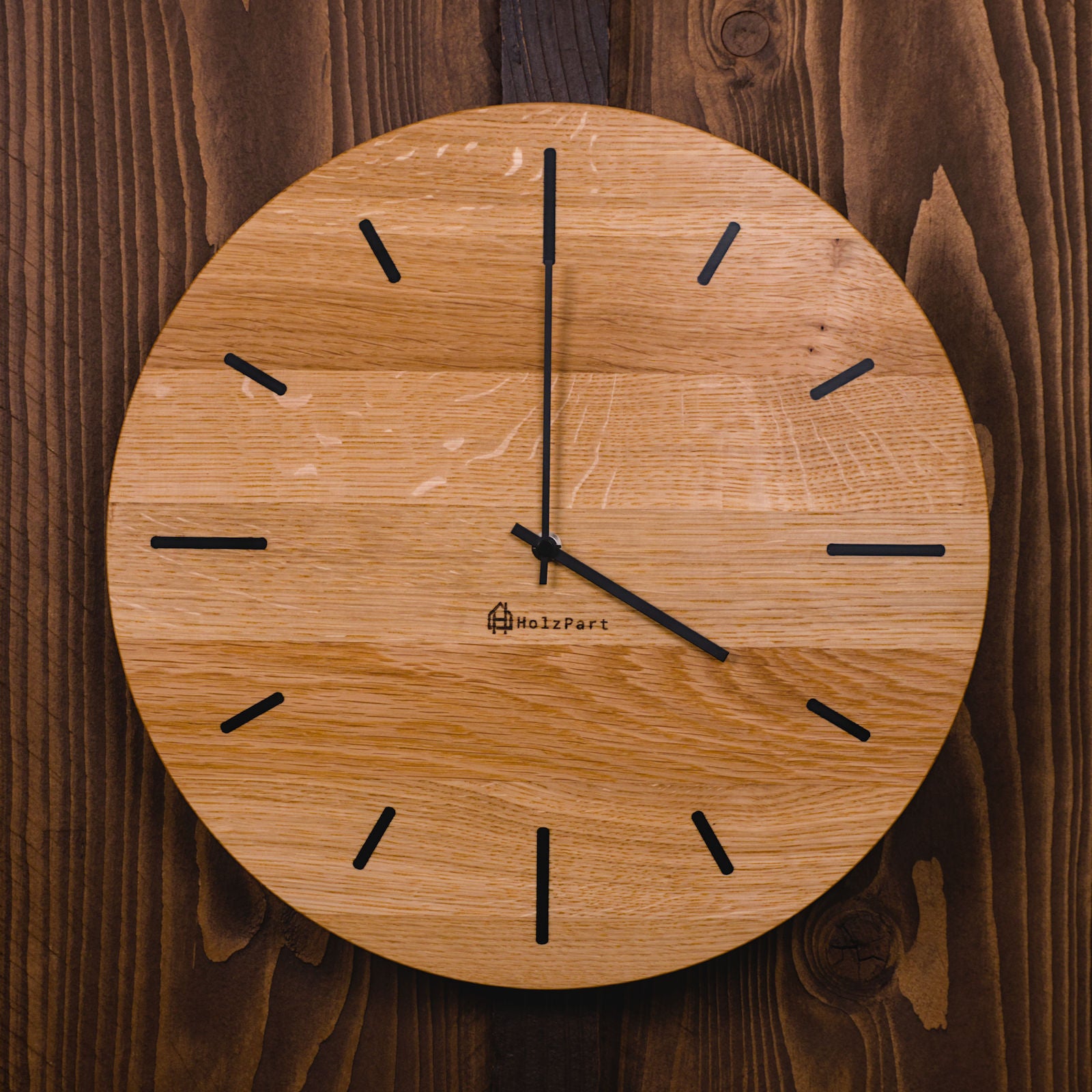 Runde Wanduhr aus klassisch geölter Eiche mit schwarzen Stundenstrichen – Frontalansicht, handgefertigt im Solothurner Unterleberberg von HolzPart.
