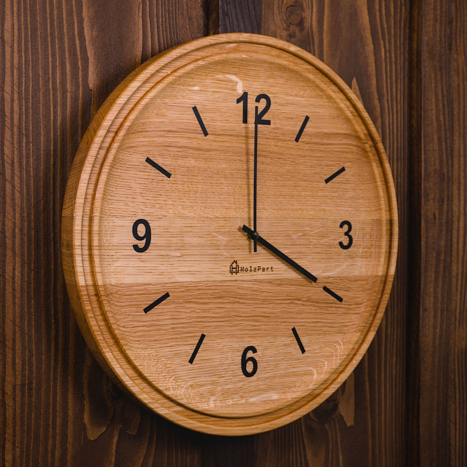 Handgefertigte runde Wanduhr mit Ziffern und doppeltem Rand aus klassisch geölter Eiche – Seitenansicht der Uhr von HolzPart Schweiz.