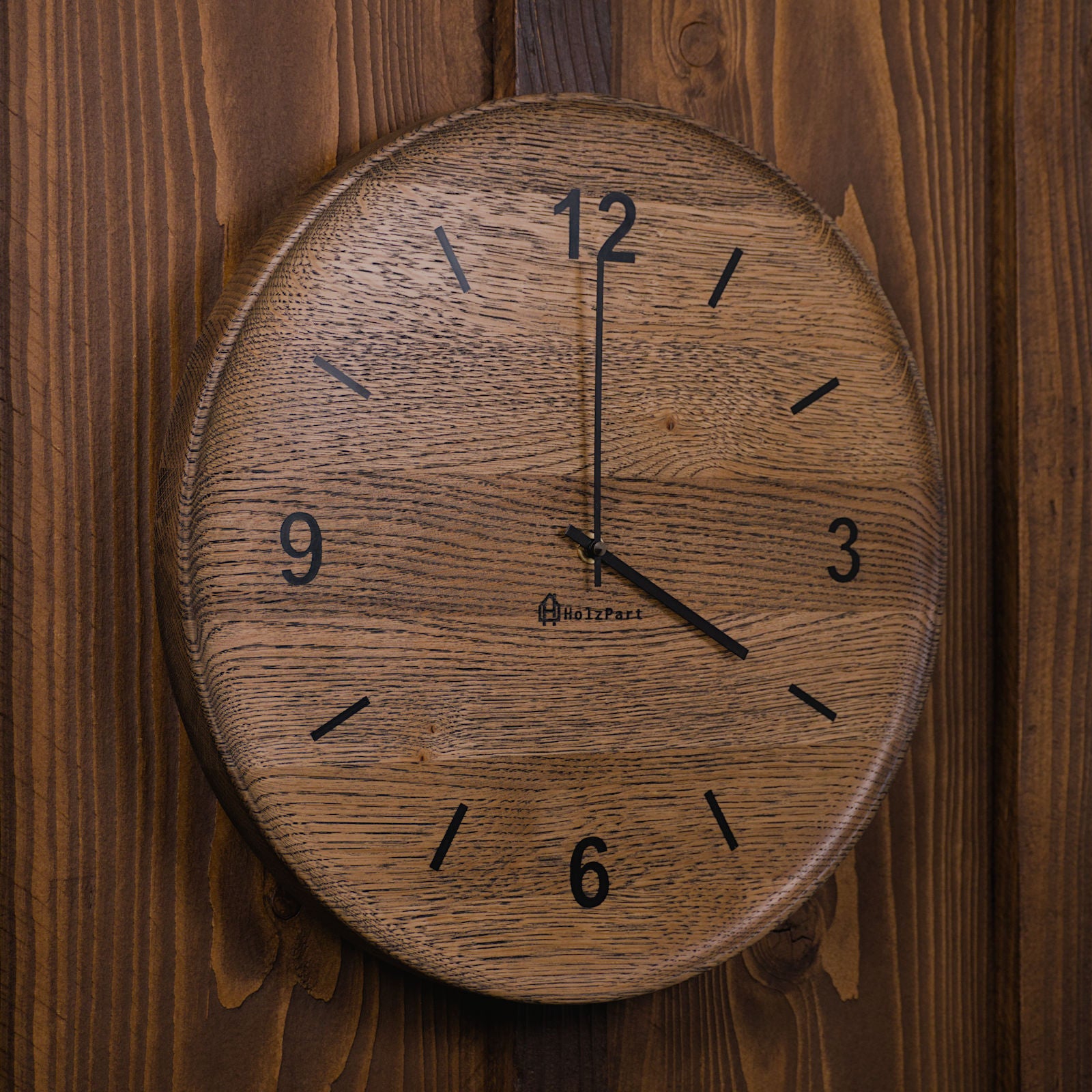 Handgefertigte runde Wanduhr mit Ziffern und flacher Schalenform aus colour geölter Eiche – Seitenansicht der Uhr von HolzPart Schweiz.