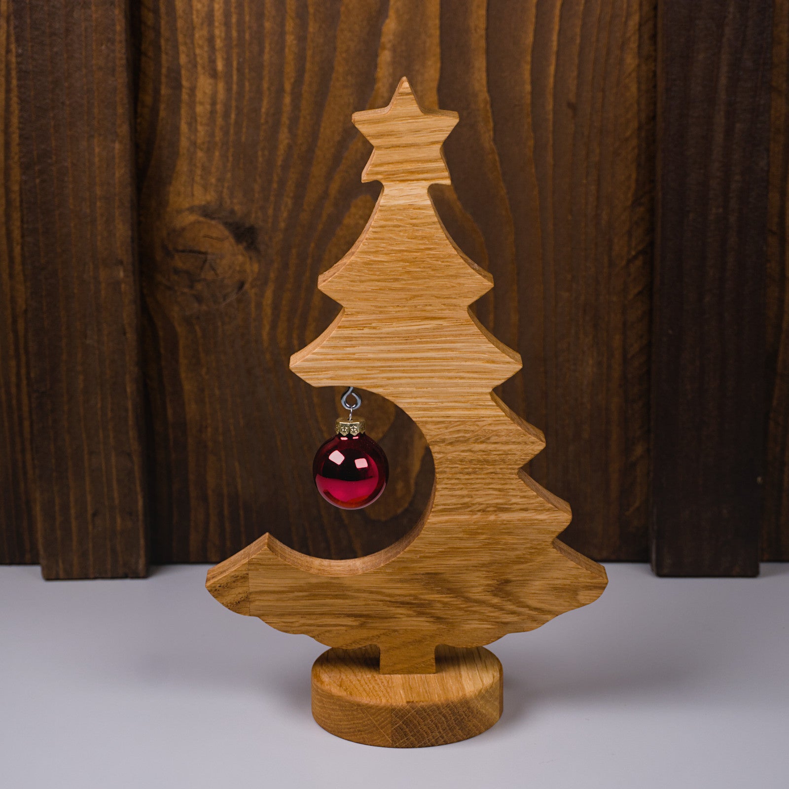 Holzweihnachtsbaum aus geöltem Eichenholz in Frontansicht, rote Kugel auf der linken Seite.