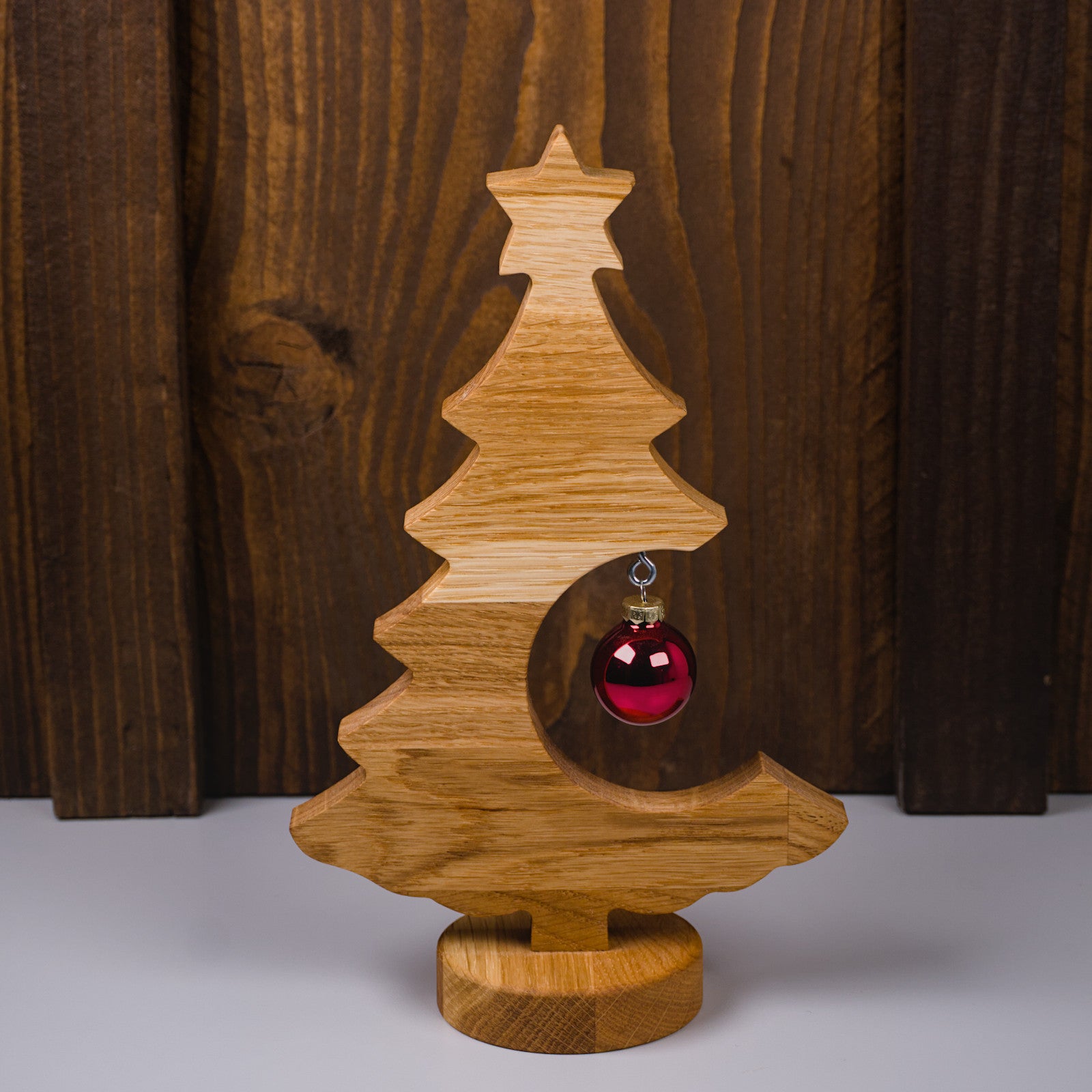 Holzweihnachtsbaum aus geöltem Eichenholz in Frontansicht, rote Kugel auf der rechten Seite.