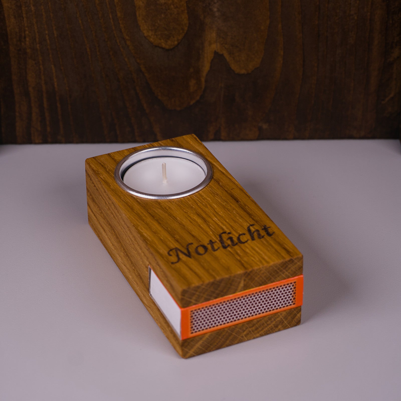 Notlicht aus Eichenholz, rechte Seitenansicht mit eingelassenem Teelicht und Reibfläche.