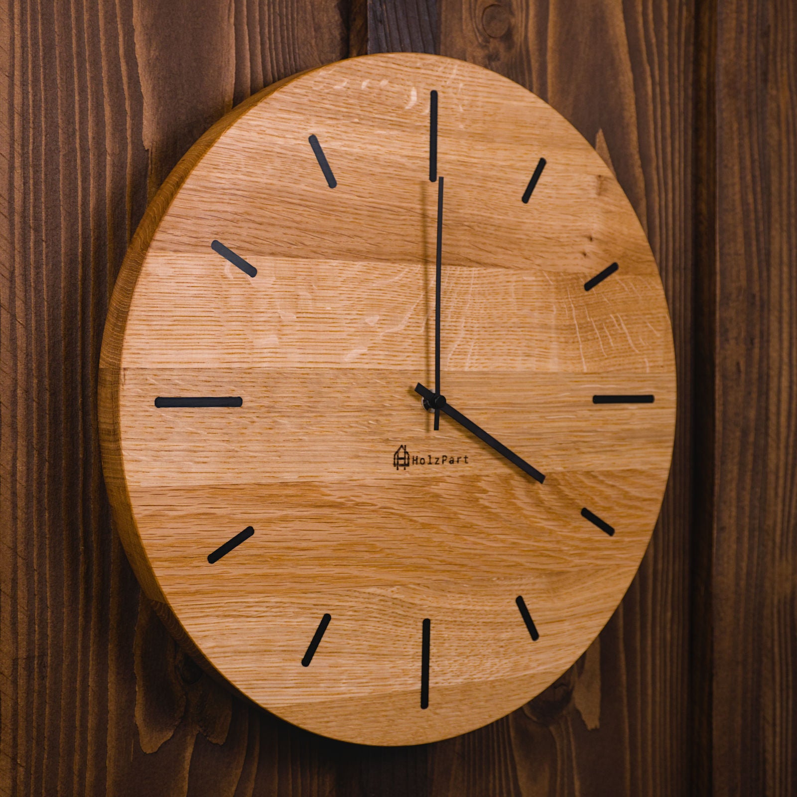 Handgefertigte runde Wanduhr aus klassisch geölter Eiche mit schwarzen Stundenmarkierungen – Seitenansicht der Uhr von HolzPart Schweiz.