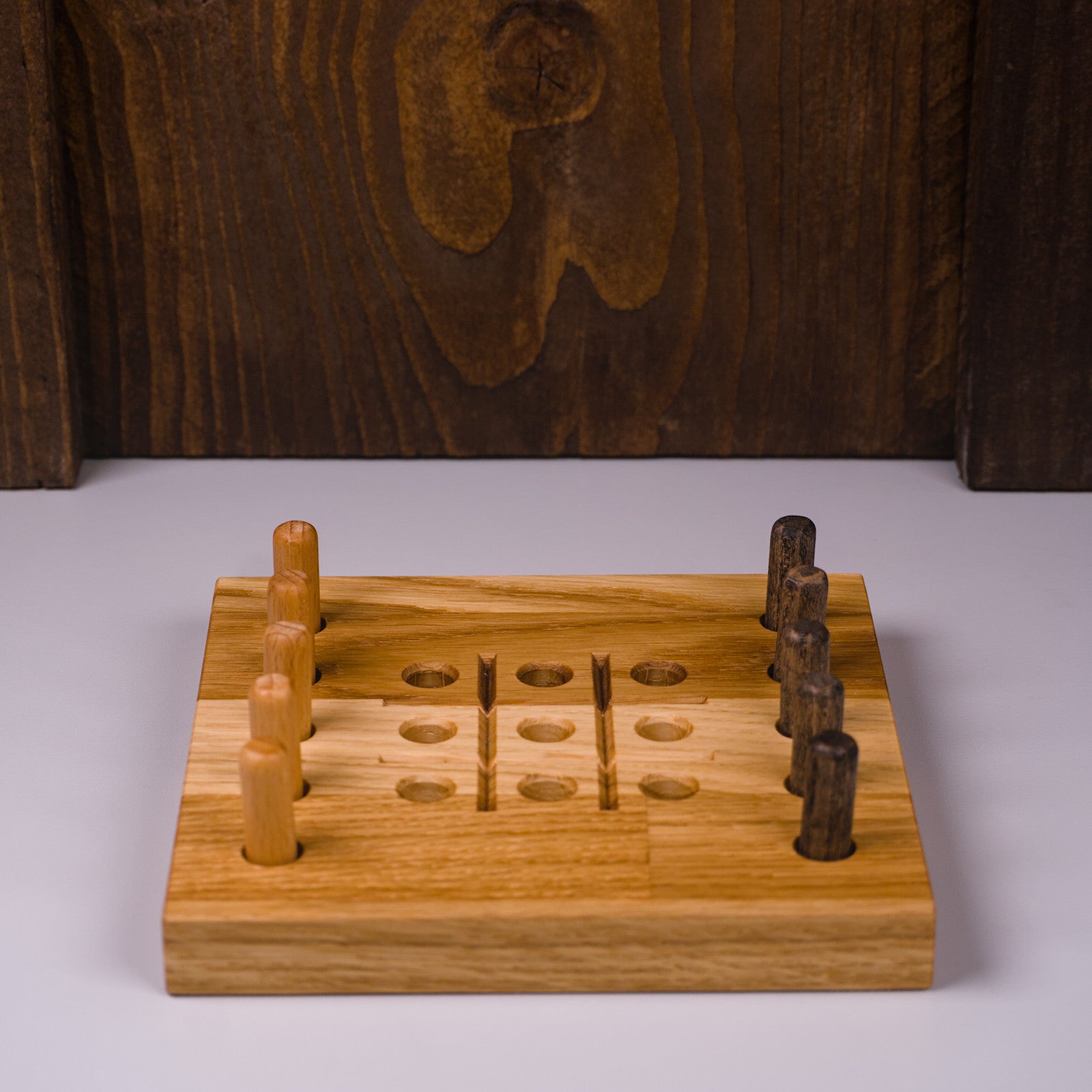 Frontansicht des Tic Tac Toe Spiels aus Eichenholz von HolzPart, mit eingelegten Spielsteinen in hell und dunkel.