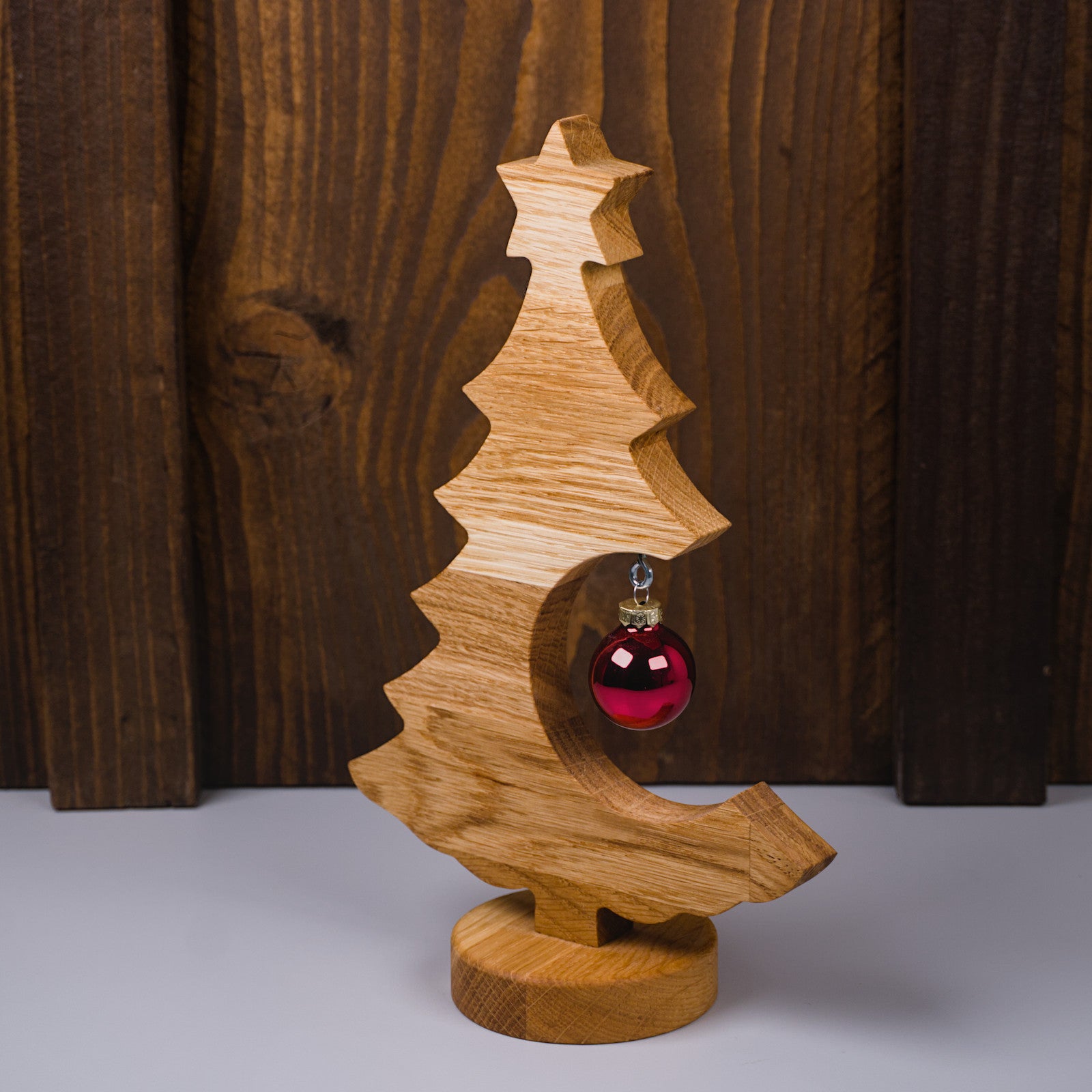 Holzweihnachtsbaum aus geöltem Eichenholz, linke Seitenansicht mit roter Kugel.